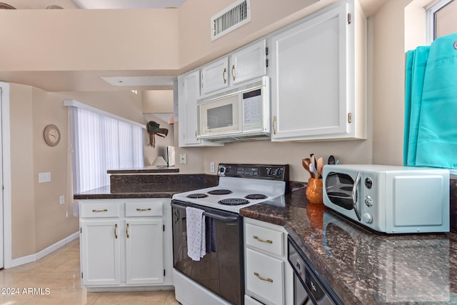 kitchen with white appliances, dark stone countertops, white cabinetry, and light tile patterned floors