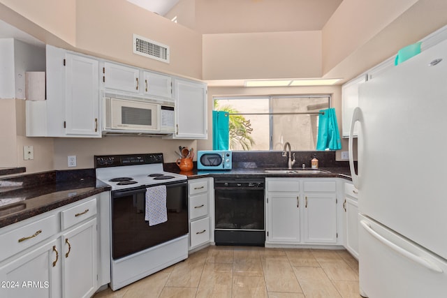 kitchen with white cabinetry, sink, dark stone counters, and white appliances