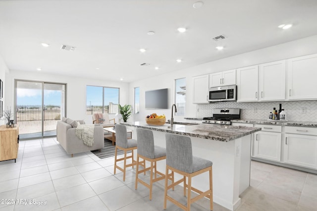 15611 W Hackamore Dr, Surprise, AZ 85387 - kitchen featuring stainless steel appliances, stone counters, light tile patterned flooring, a breakfast bar, and recessed lighting