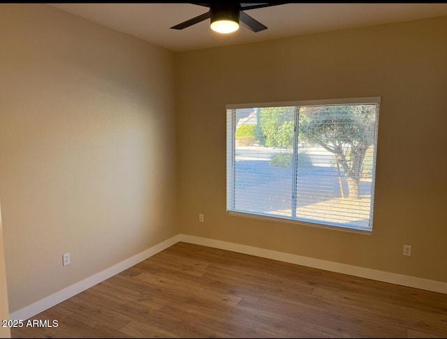 empty room featuring ceiling fan, plenty of natural light, and wood-type flooring