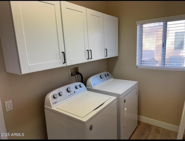 laundry room with a healthy amount of sunlight, hardwood / wood-style floors, cabinets, and washer and dryer