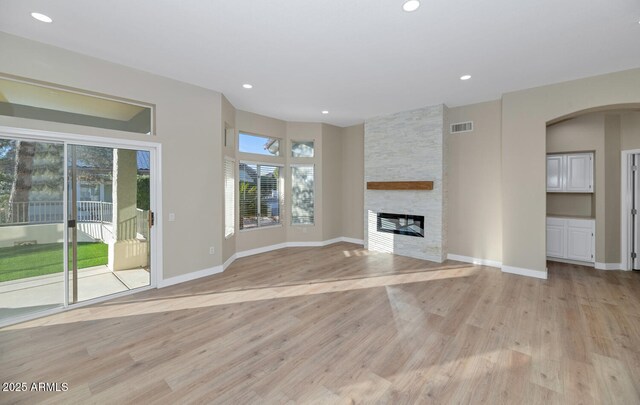 unfurnished living room featuring light wood-type flooring and a stone fireplace