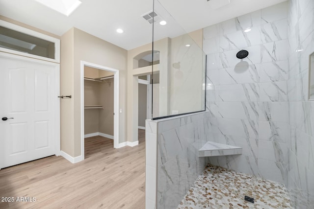 bathroom with wood-type flooring and a tile shower