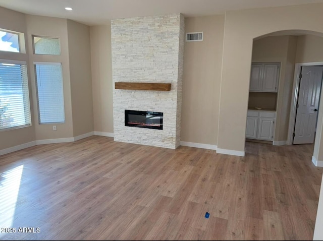 unfurnished living room featuring light hardwood / wood-style flooring and a stone fireplace