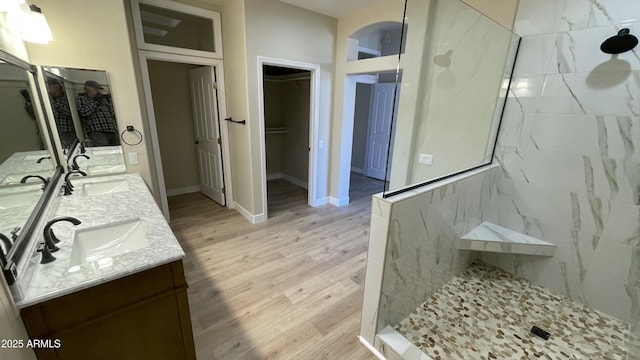 bathroom featuring vanity, tiled shower, and wood-type flooring