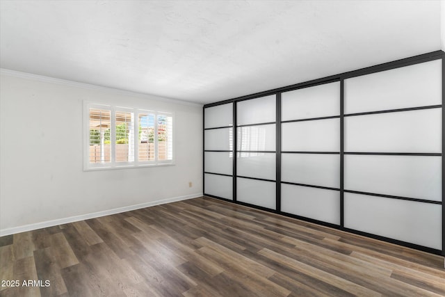 empty room with ornamental molding, dark hardwood / wood-style floors, and a textured ceiling