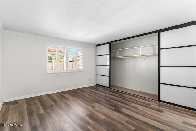 unfurnished bedroom with crown molding, dark hardwood / wood-style floors, and a closet