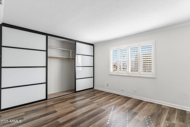 unfurnished bedroom featuring hardwood / wood-style flooring, crown molding, and a closet