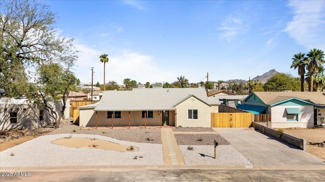 view of front of property featuring a gate, concrete driveway, fence, and stucco siding