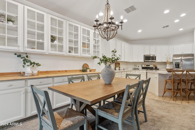 dining area featuring light tile patterned floors, lofted ceiling, and an inviting chandelier