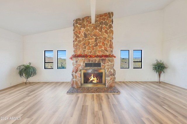 unfurnished living room featuring a fireplace, light wood-type flooring, vaulted ceiling, and plenty of natural light