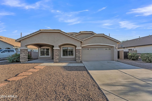 view of front of property with concrete driveway, an attached garage, stone siding, and stucco siding