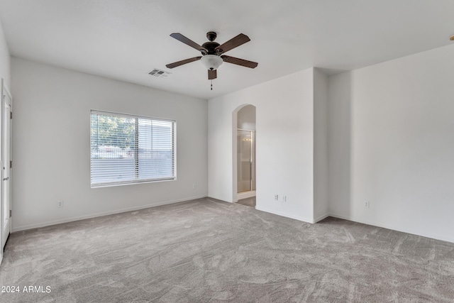 spare room featuring arched walkways, visible vents, a ceiling fan, and carpet