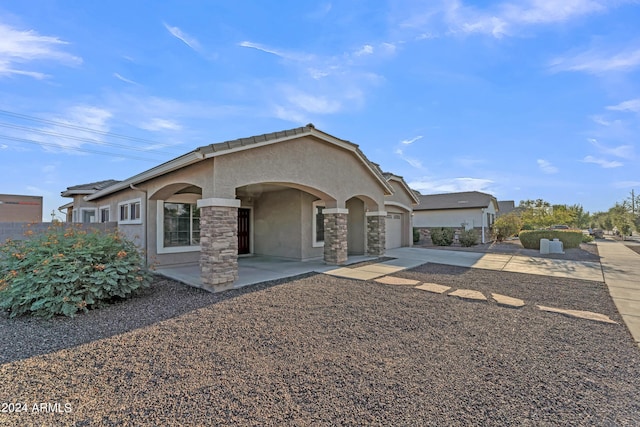 view of front facade with stone siding, stucco siding, driveway, and a garage