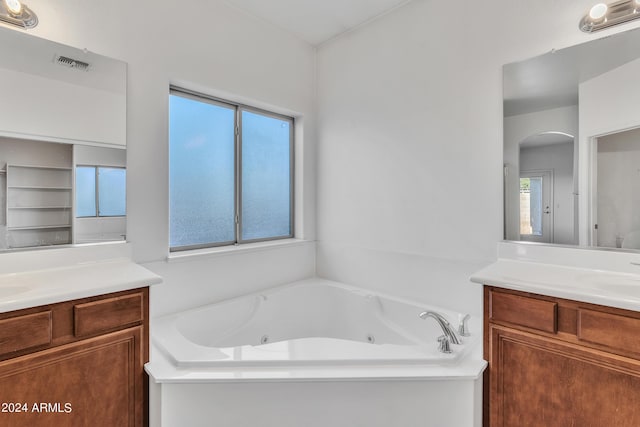 bathroom featuring visible vents, a sink, a jetted tub, and two vanities