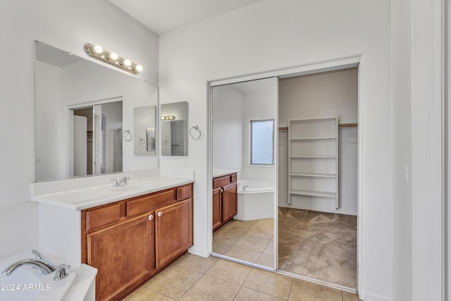 bathroom with a walk in closet, a bath, vanity, and tile patterned flooring