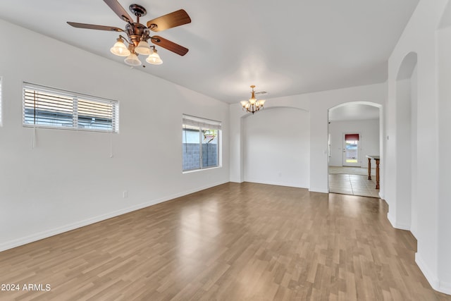 unfurnished room with ceiling fan with notable chandelier and light wood-type flooring