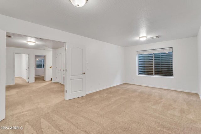 spare room featuring visible vents, light carpet, and baseboards