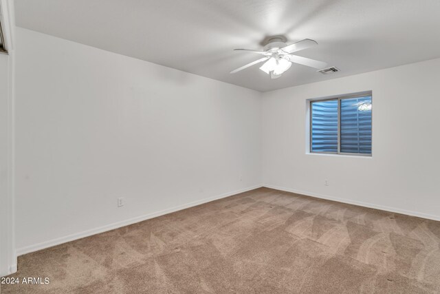 empty room featuring carpet flooring, a ceiling fan, visible vents, and baseboards