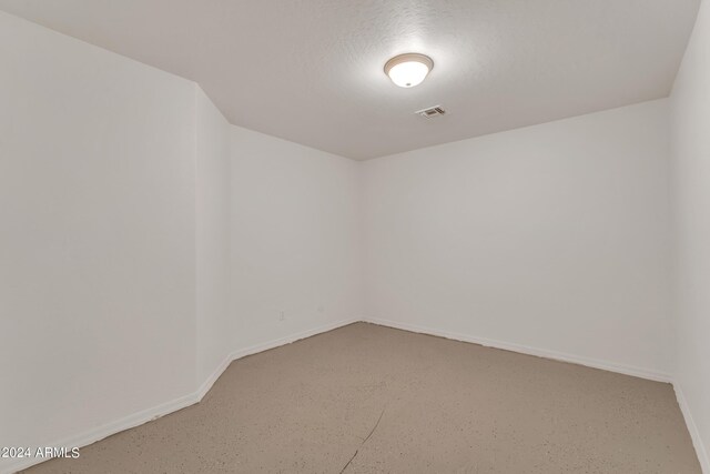 spare room with visible vents, baseboards, a textured ceiling, and concrete floors