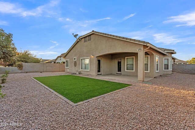 rear view of property with a fenced backyard, stucco siding, a yard, and a patio