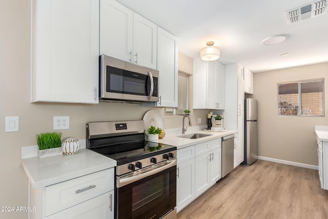 kitchen with sink, white cabinets, light hardwood / wood-style floors, and appliances with stainless steel finishes