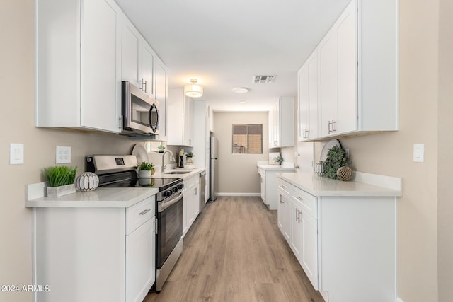 kitchen with white cabinets, light hardwood / wood-style floors, sink, and appliances with stainless steel finishes