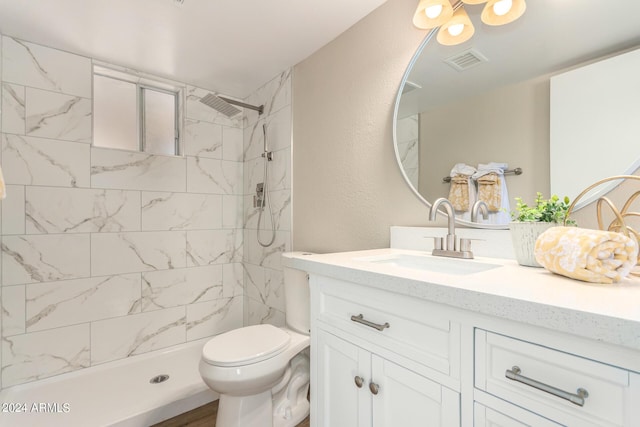 bathroom with vanity, toilet, and a tile shower