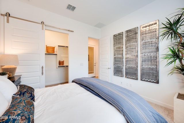 7854 W Tether Trl, Peoria, AZ 85383 - bedroom with a barn door, baseboards, a walk in closet, carpet flooring, and a closet