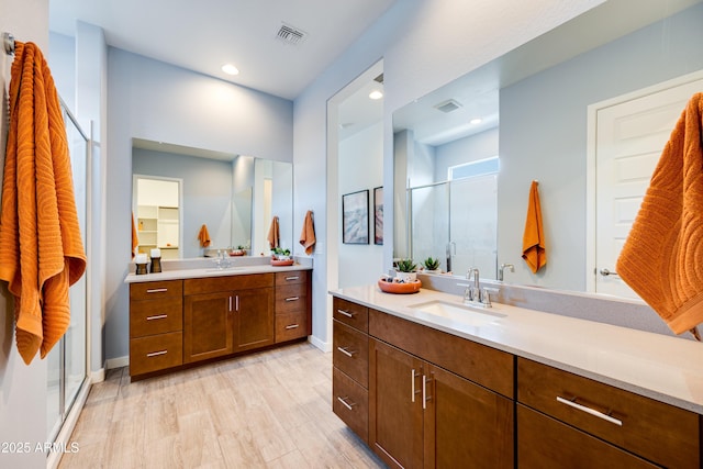 7854 W Tether Trl, Peoria, AZ 85383 - bathroom featuring a shower stall, two vanities, wood finished floors, baseboards, and recessed lighting