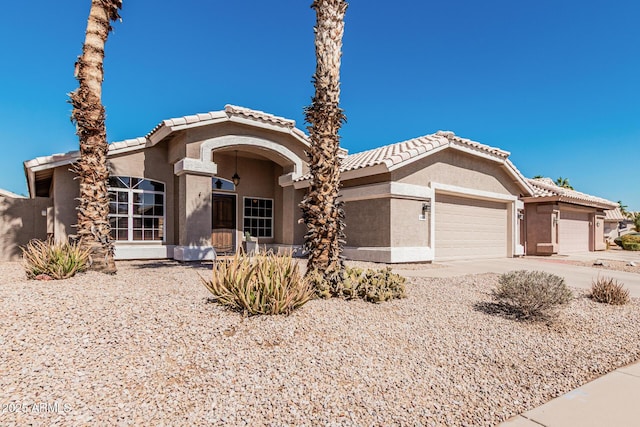 view of front of house with driveway, a tiled roof, an attached garage, and stucco siding