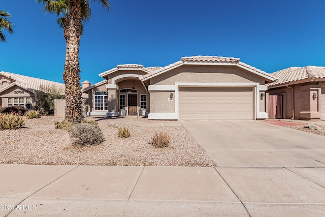 view of front of home with concrete driveway, an attached garage, a tile roof, and stucco siding