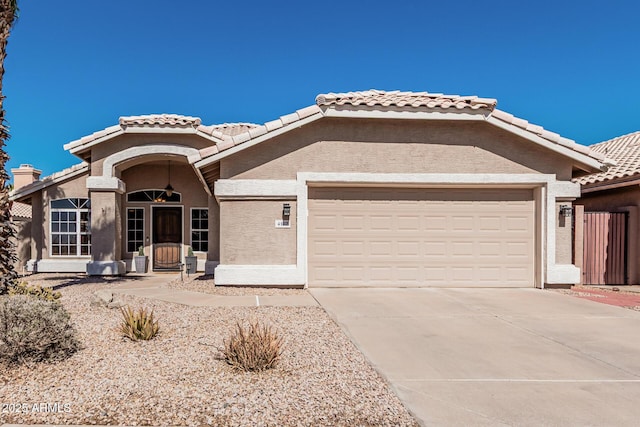 view of front of property featuring driveway, an attached garage, a tiled roof, and stucco siding