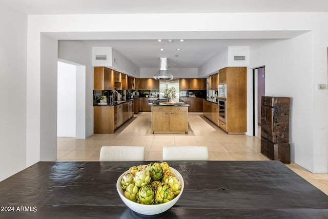 kitchen featuring brown cabinets, light tile patterned floors, a center island, and dark countertops
