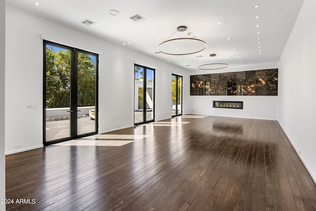 empty room with a glass covered fireplace, recessed lighting, wood-type flooring, and visible vents