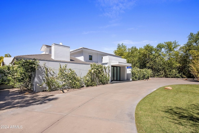 exterior space with a chimney, a front yard, and stucco siding