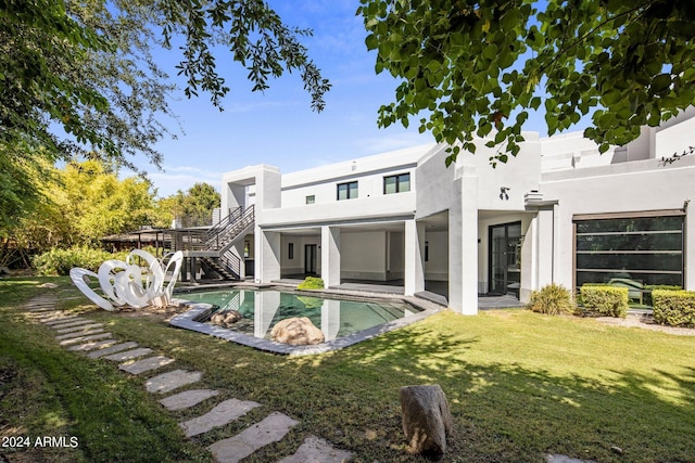 back of property featuring stucco siding, a lawn, a patio, stairs, and an outdoor pool