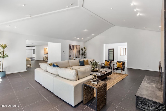 living area with dark tile patterned flooring, baseboards, and high vaulted ceiling