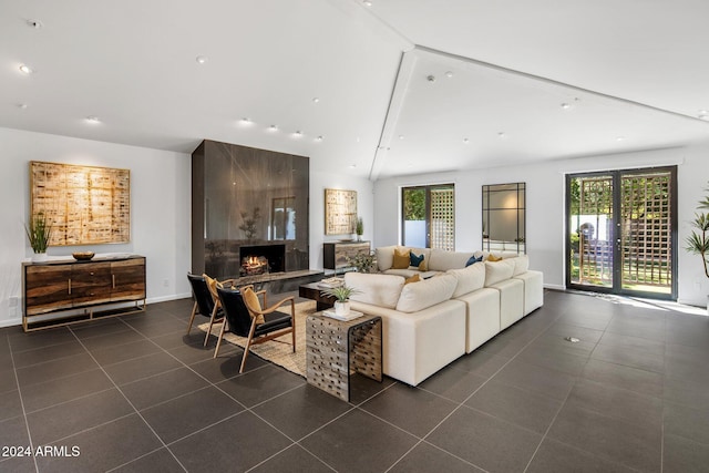 living room featuring a wealth of natural light, a high end fireplace, vaulted ceiling with beams, and dark tile patterned flooring