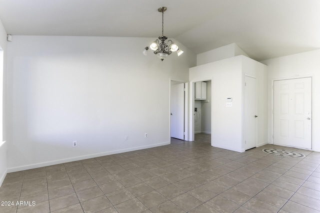 spare room featuring tile patterned flooring, a notable chandelier, and vaulted ceiling