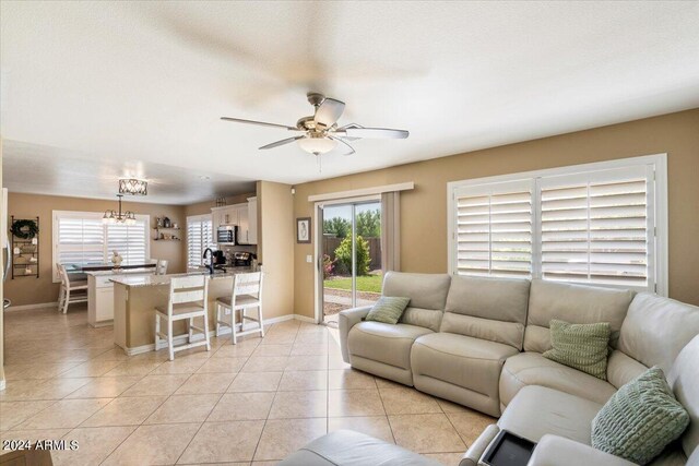 living room with a textured ceiling, ceiling fan, sink, and light tile patterned floors