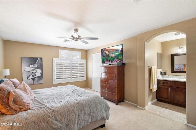 bedroom with ceiling fan, ensuite bathroom, and light carpet