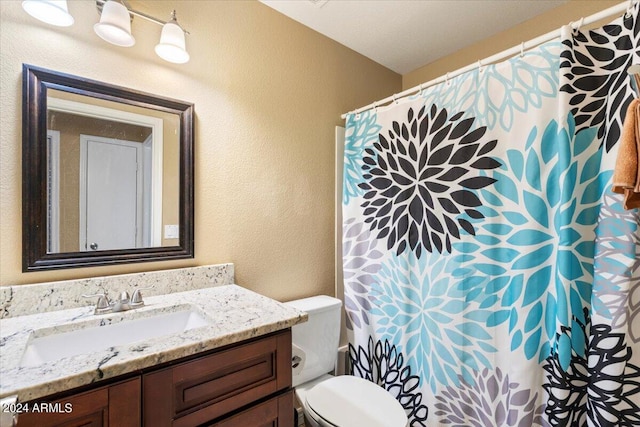 bathroom featuring walk in shower, toilet, and vanity