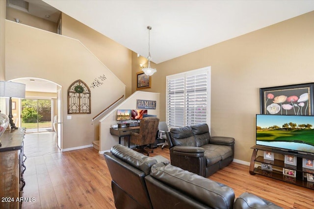 living room featuring light wood-type flooring and a towering ceiling