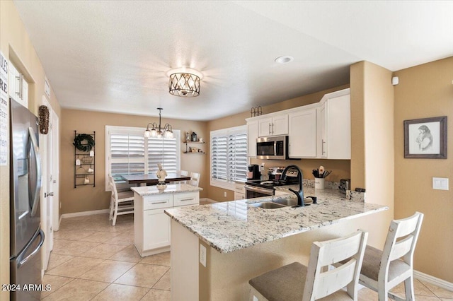 kitchen featuring decorative light fixtures, a wealth of natural light, stainless steel appliances, and kitchen peninsula