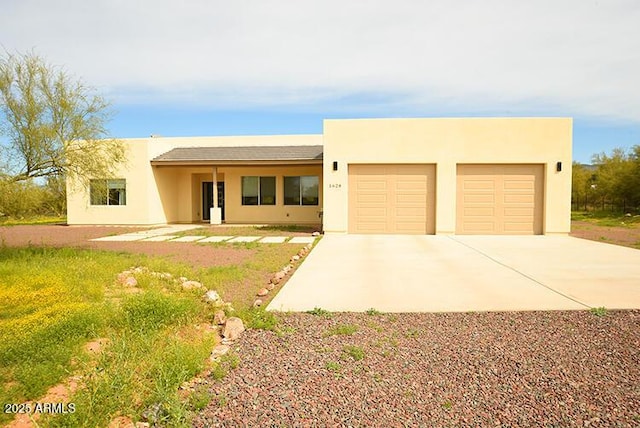 pueblo-style house featuring driveway, an attached garage, and stucco siding