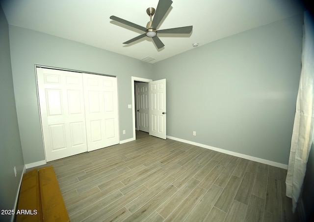 unfurnished bedroom featuring a closet, ceiling fan, baseboards, and wood finished floors