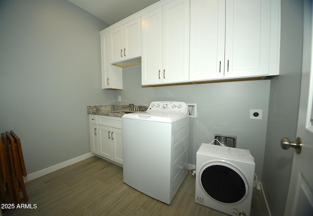 clothes washing area featuring cabinet space, baseboards, washer / clothes dryer, and light wood finished floors