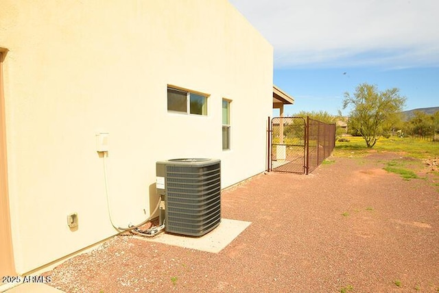 view of home's exterior featuring stucco siding, a gate, and central air condition unit