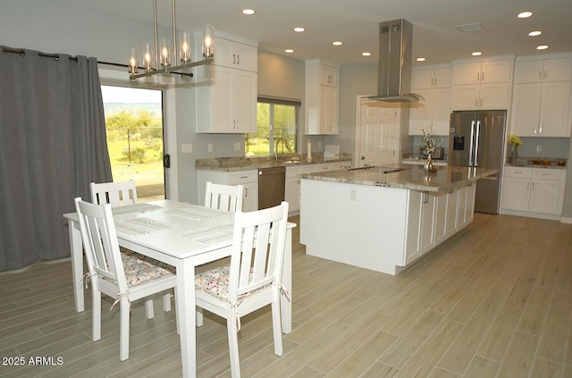 kitchen with appliances with stainless steel finishes, wood finish floors, island exhaust hood, and white cabinets